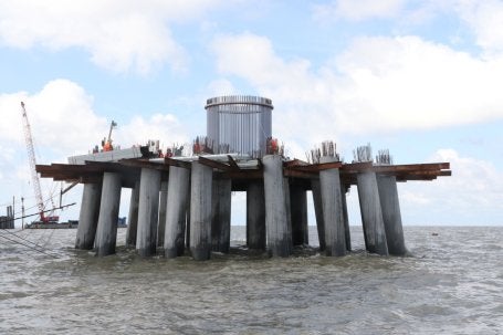 Frente a la costa de Ninh Thuan, en Vietnam, trabajadores construyen la torre de una turbina eólica.