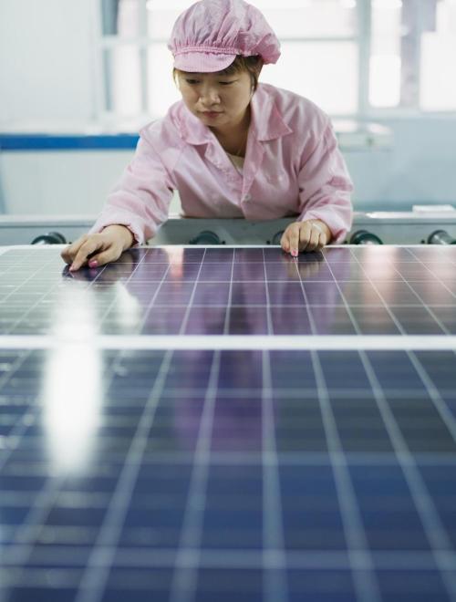 A factory worker assembles solar panels in Dezhou, China. Photo by Cultura Creative RF/Alamy